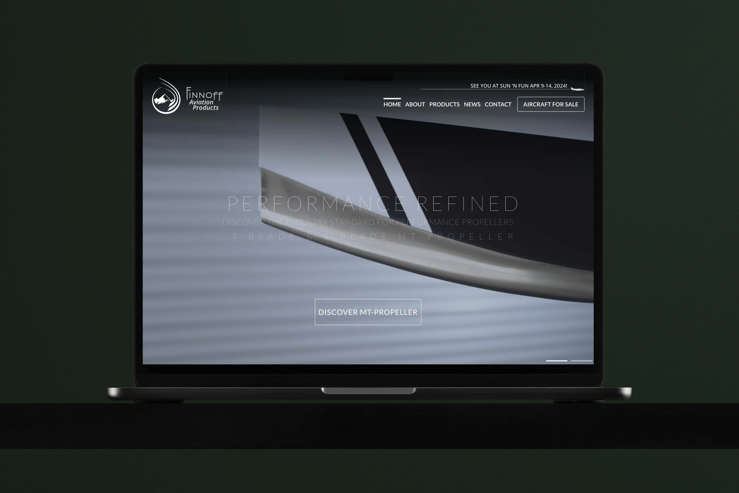 A MacBook on a dark table showing the finnoff.com home page: Performance Refined over the MT-Propeller film