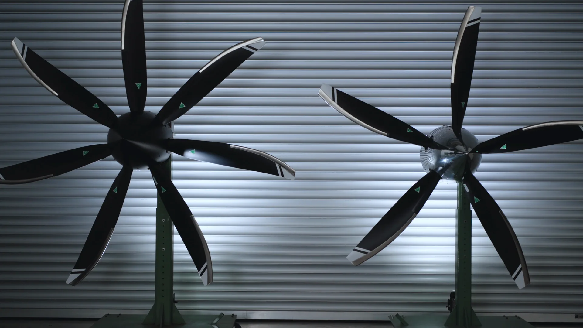 MT seven-blade and five-blade propellers on stands against a ribbed hangar wall