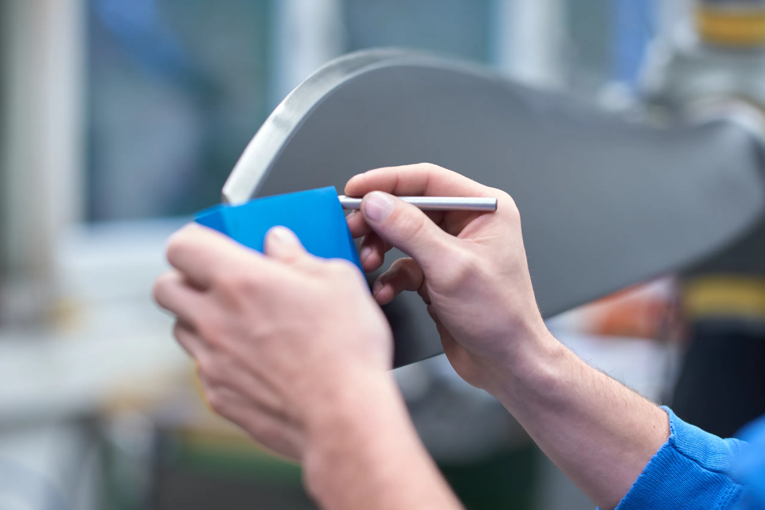 A worker in blue marks a propeller blade with a pen and a blue template at the MT Propeller factory in Straubing