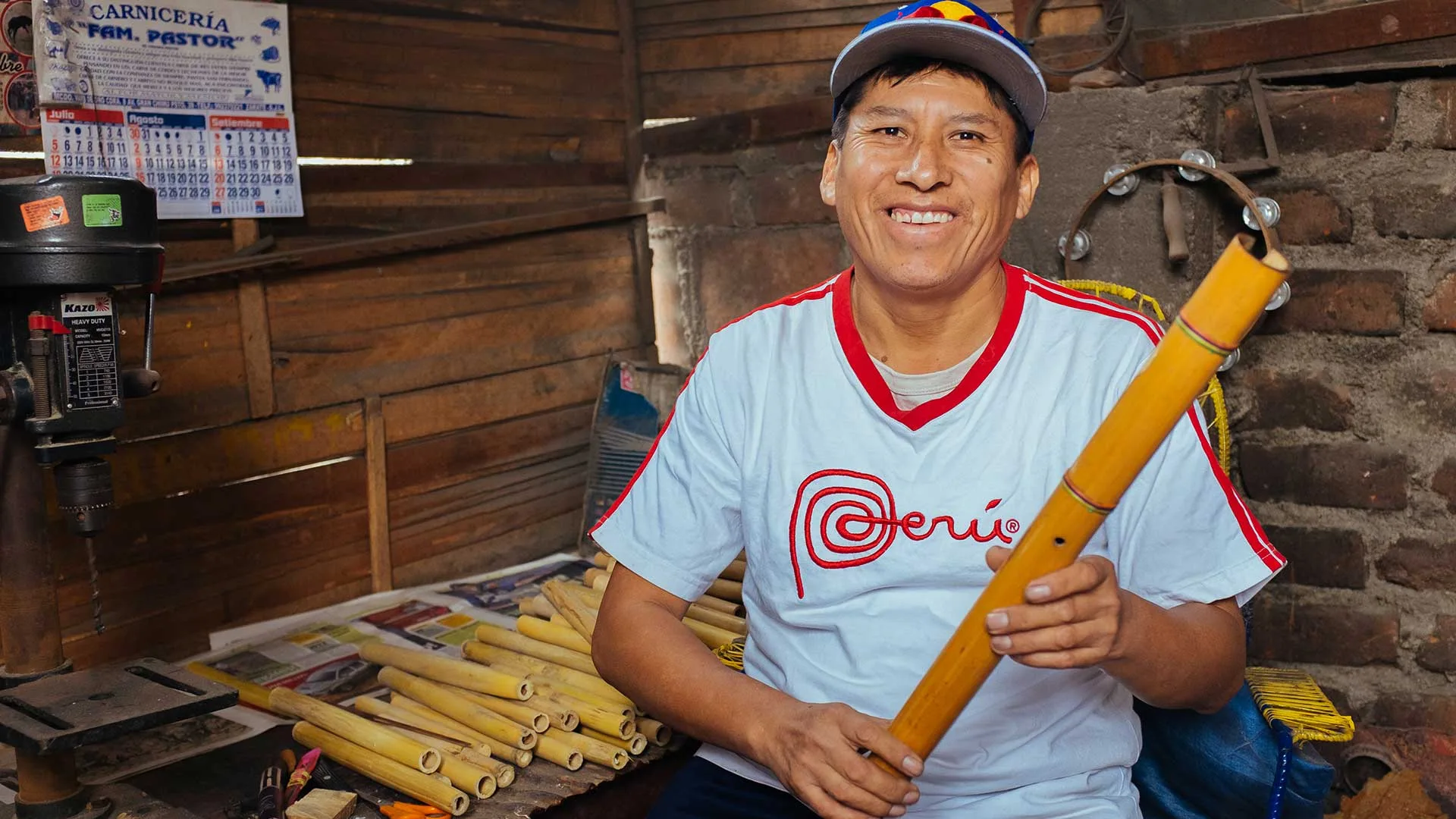 Cover of Meet the Artisans: Cispe: Cispe smiles holding a bamboo flute in his workshop, beside cut cane tubes and a drill press