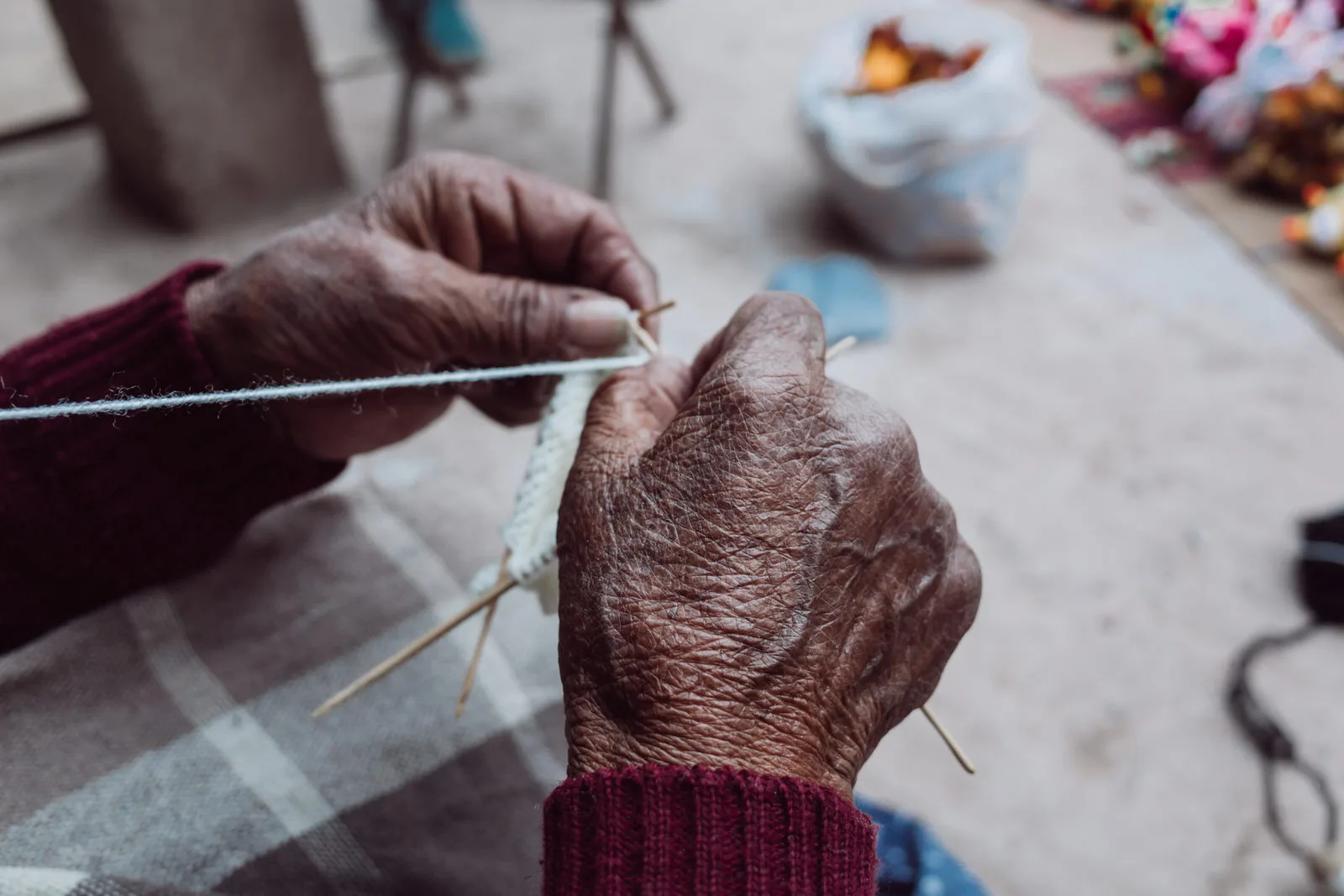 Close-up of Mabel’s grandmother’s hands knitting white yarn on wooden needles